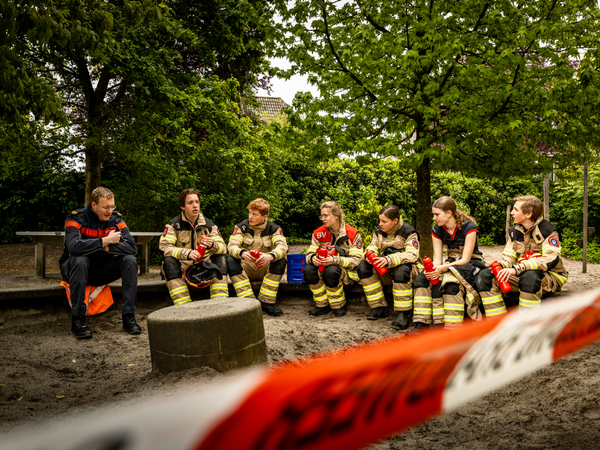 Jeugdbrandweerleden zitten tijdens een wedstrijd samen in overleg.