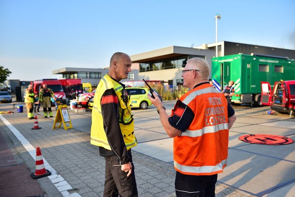 twee personen overleggen voor brandweervoertuigen tijdens veiligheidsdag