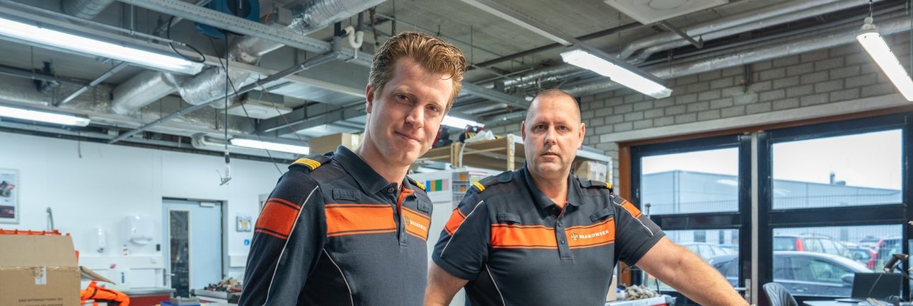 Twee mannen in brandweeruniform staan in een werkplaats