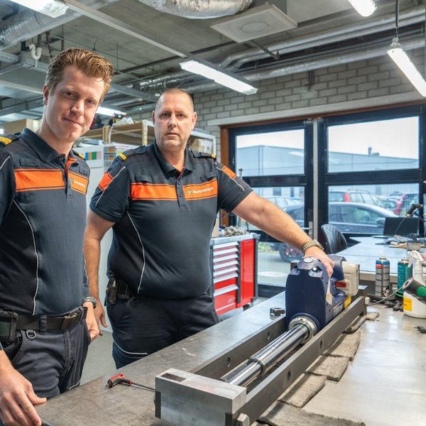 Twee mannen in brandweeruniform staan in een werkplaats