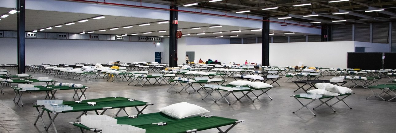 Rijen veldbedden in een grote hal