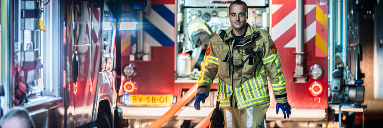 Een brandweerman loopt voor een brandweerwagen