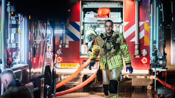Een brandweerman loopt voor een brandweerwagen