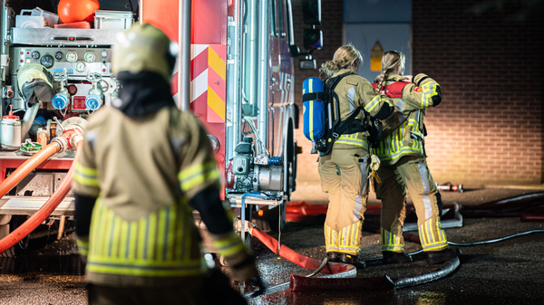Brandweervrouwen staan bij een brandweervoertuig