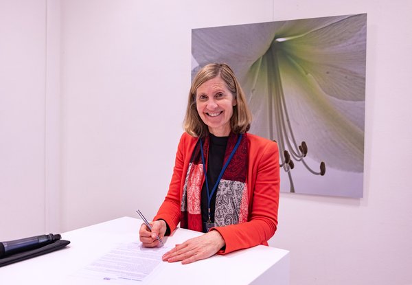 Vrouw in rood vestje ondertekent charter diversiteit