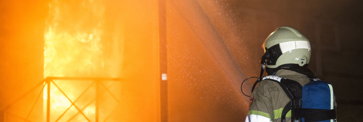 Brandweerpersoon in bluspak blust een brand