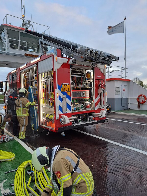 Brandweerlieden oefenen aan boord van een schip met een brandweervoertuig en brandslangen