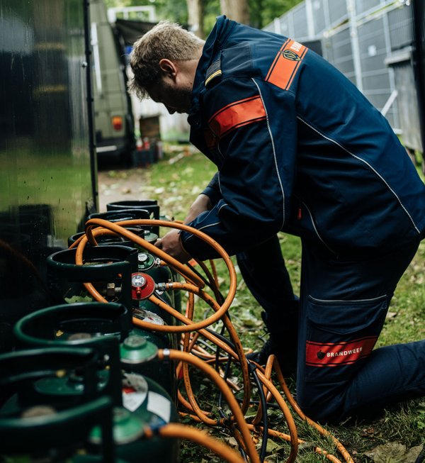 foto van een brandweerman die een gasfles controleert