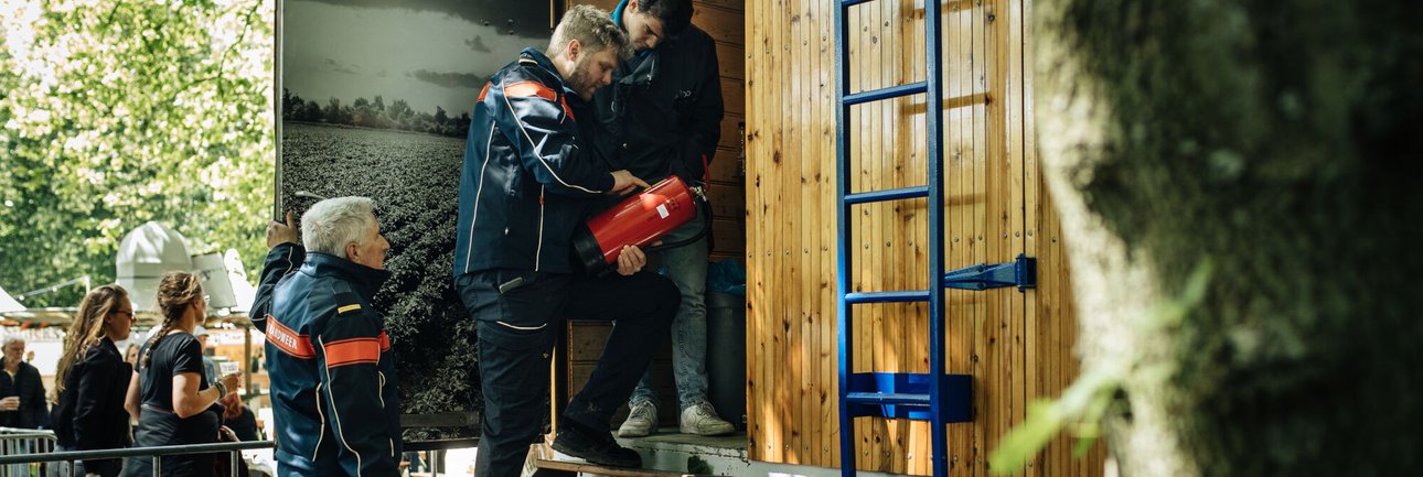 foto van twee brandweermannen die in gesprek zijn met een ondernemer