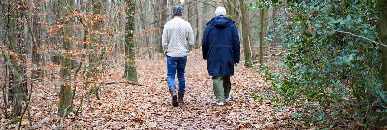 Foto van twee wandelende mensen in een bos