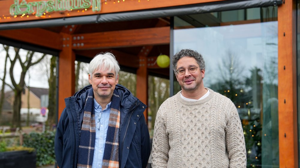 foto van twee mannen voor een dorpshuis