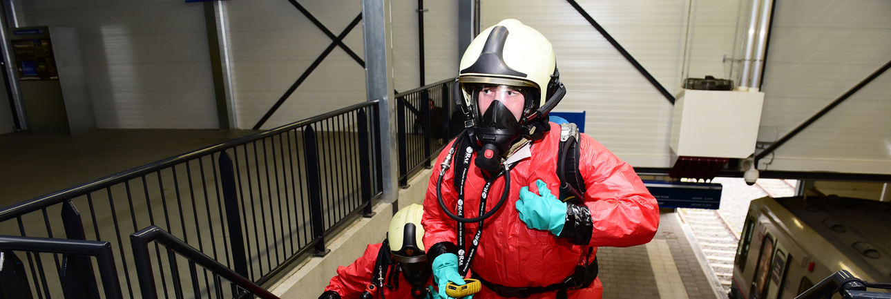 Twee mensen in chemisch beschermende pakken en helmen