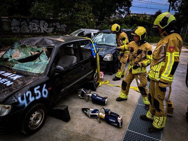 Brandweervrijwilligers oefenen met hydraulisch gereedschap bij een auto tijdens een technische hulpverleningsoefening