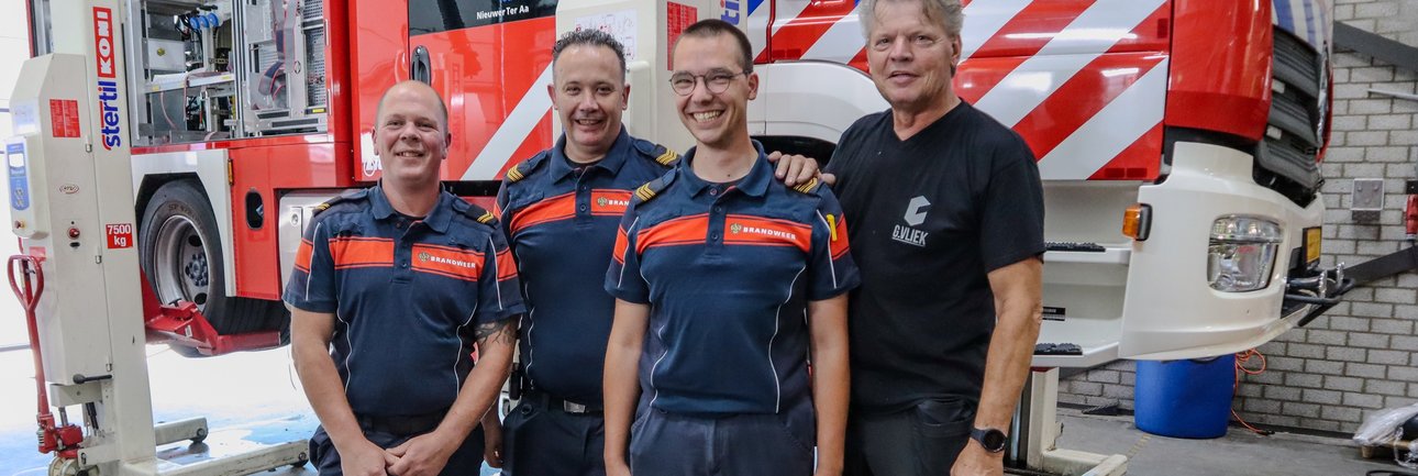 Vier brandweermensen voor een voertuig