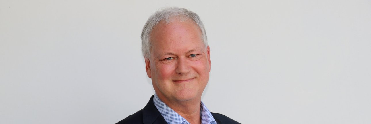 Marc Sprenger in pak, kijkt naar camera met een lach