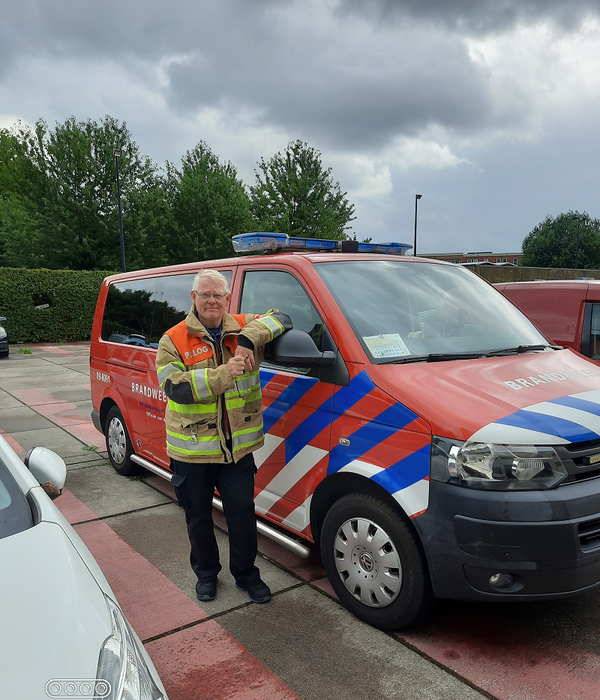 Brandweerman in blusjas naast een brandweervoertuig