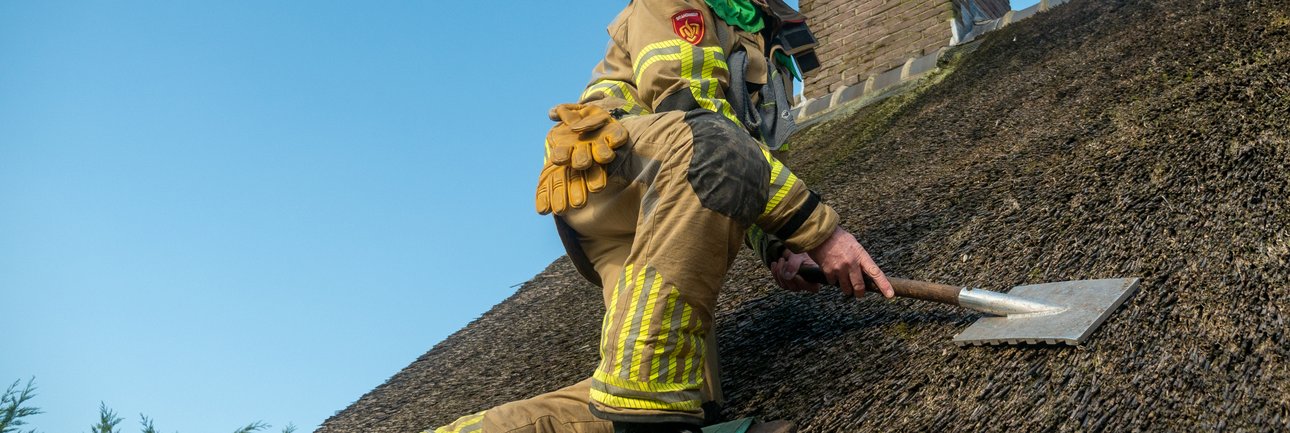 Brandweerman op rieten dak
