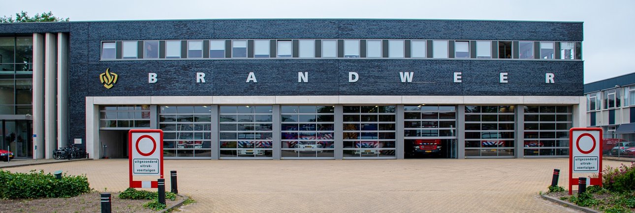 Grijs gebouw met grote rolluiken en de tekst "brandweer" op de gevel