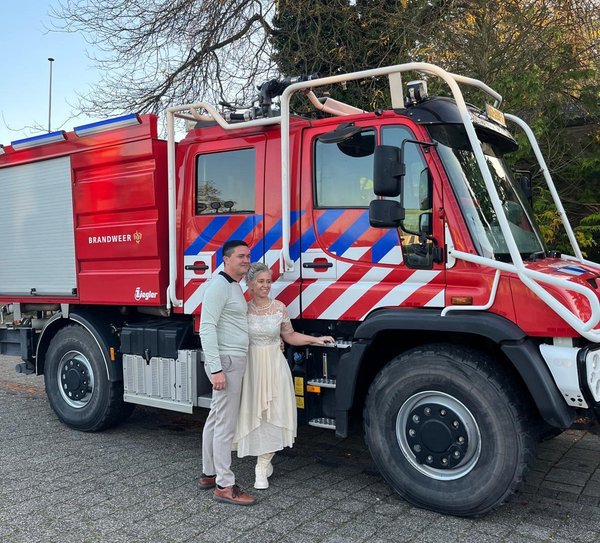 Brandweermensen poseren voor brandweervoertuig