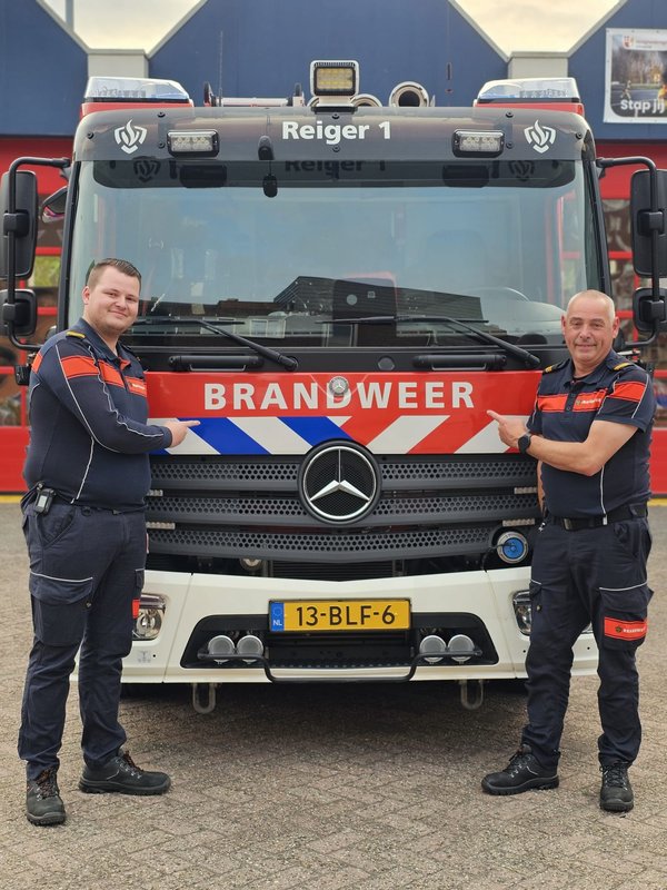 Vader en zoon, Rene en Kevin, poseren in brandweerkleding voor brandweervoertuig Vianen.