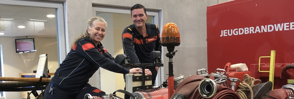 2 brandweermensen poseren, kijken lachend in de camera.