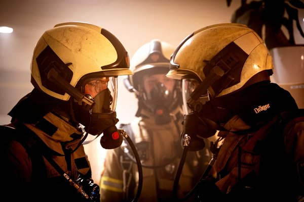 Brandweermensen met ademlucht maskers staan geposeerd