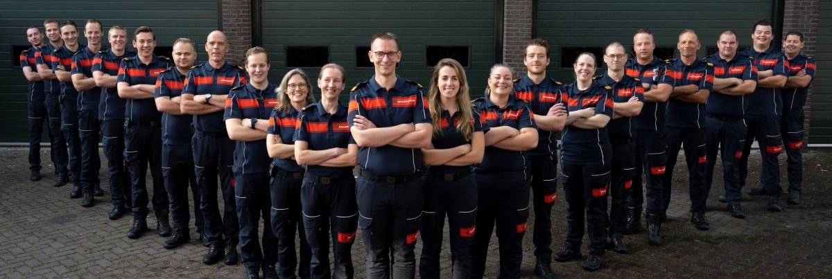 Brandweermensen in huniform staan geposeerd voor rolluiken