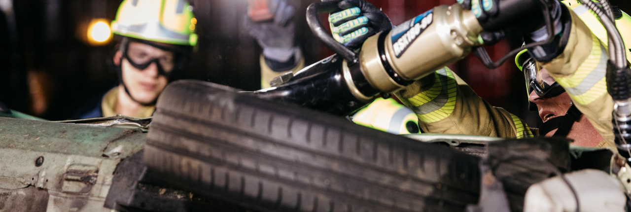 Brandweermensen openen met snijapparatuur een auto op zijn kant