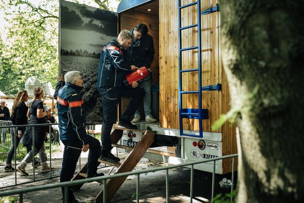 Drie brandweermannen staan in een wagen een blusfles te bekijken
