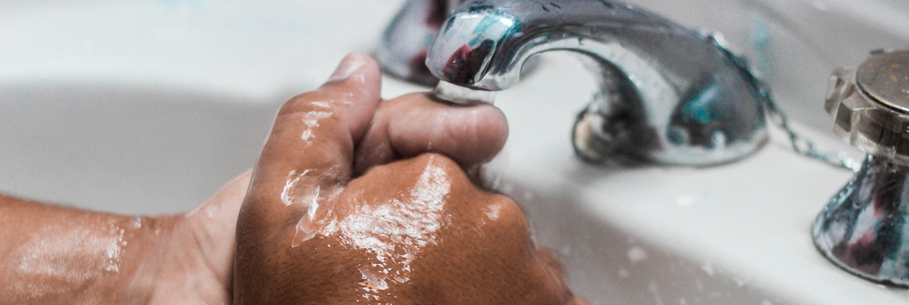 Handen die onder een kraan gewassen worden