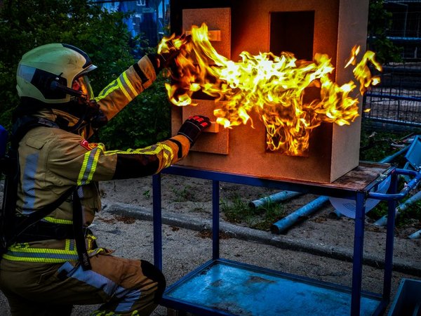 Brandweervrijwilliger blust een brand in een poppenhuis tijdens een demonstratie op een open dag van de brandweer.