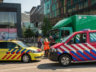Een ambulancewagen, brandweerbusje en groene vrachtwagen staan geparkeerd bij een incident