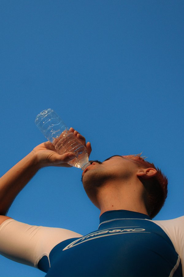 "Man die water drink uit flesje met heldere blauwe lucht"