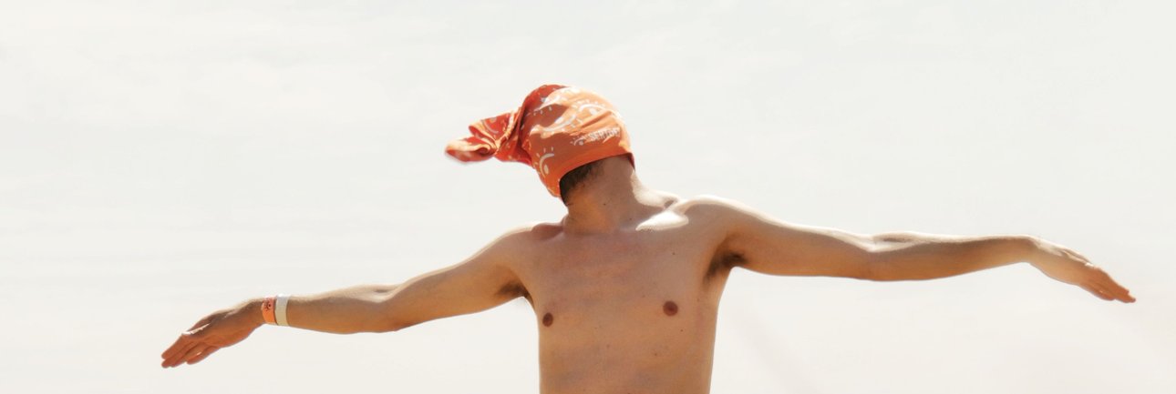 "Man met handdoek over zijn hoofd en in granenveld die geniet van de zon"