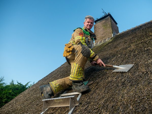 Brandweerman op rieten dak