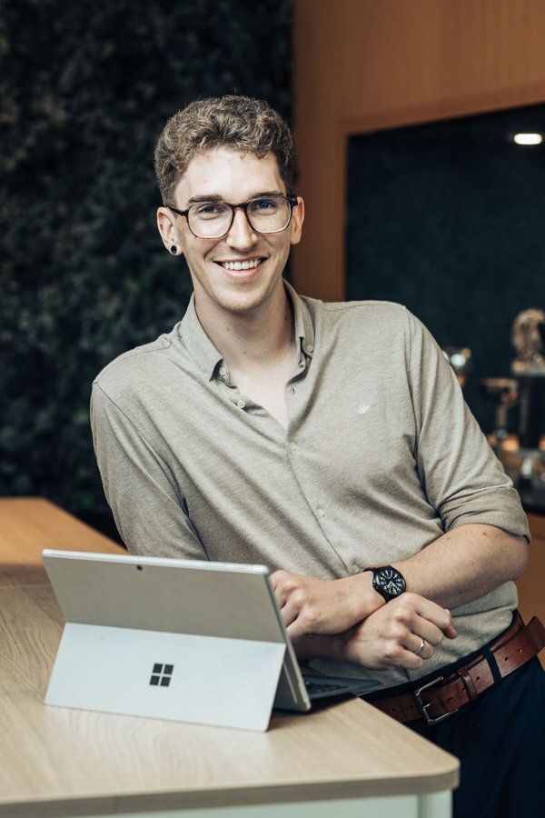Jonas Geusebroek staat met laptop op tafel in een warm uitziende kantooromgeving